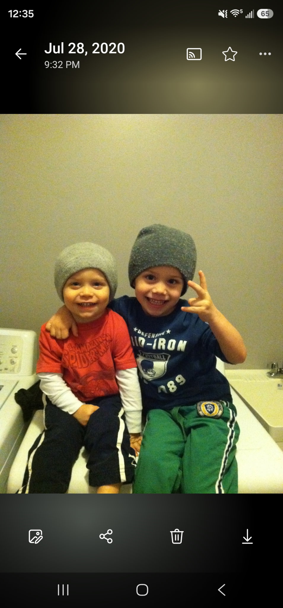 Two small children wearing knit hats, sitting side by side