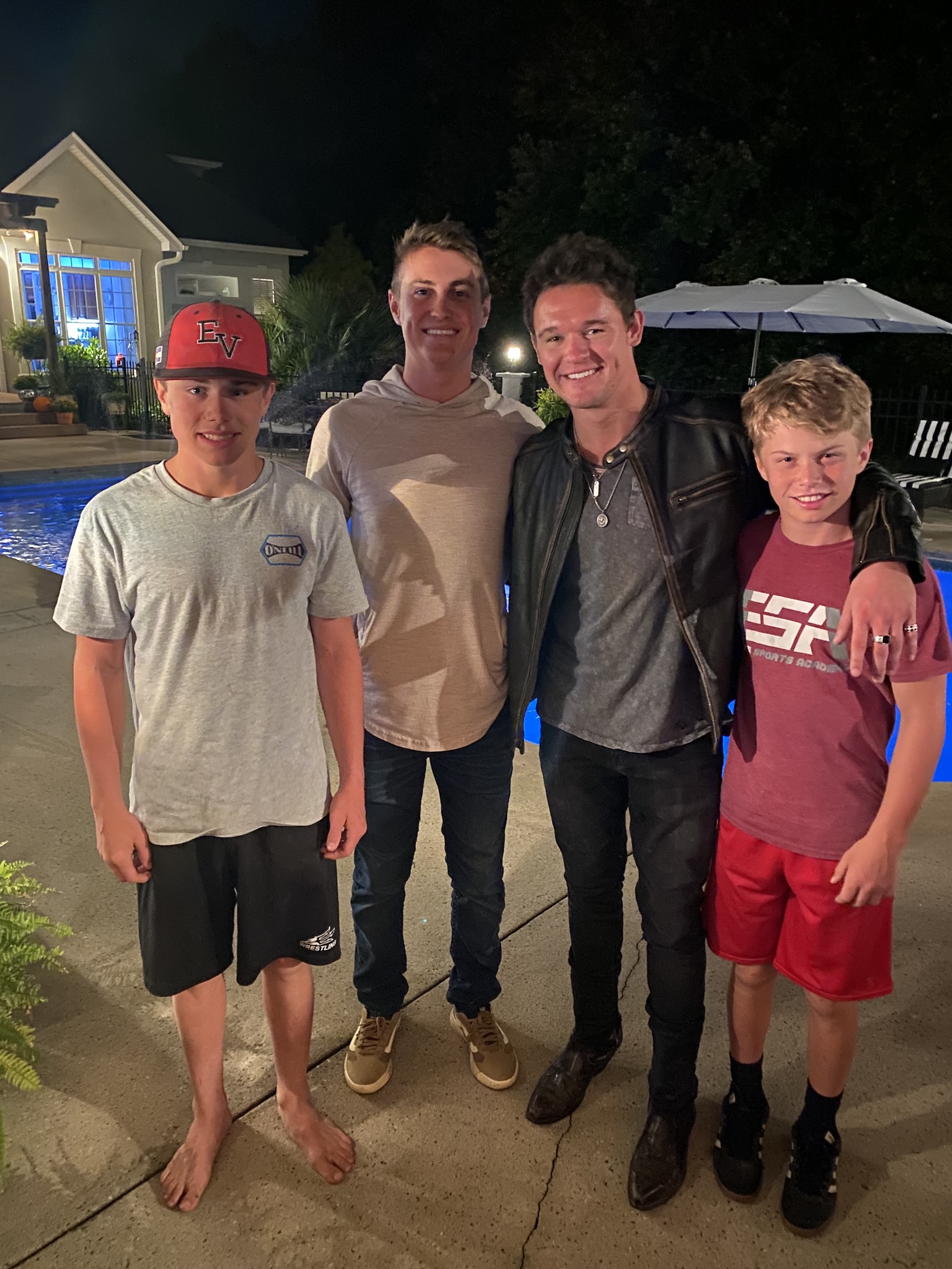 Four people standing beside a swimming pool at night