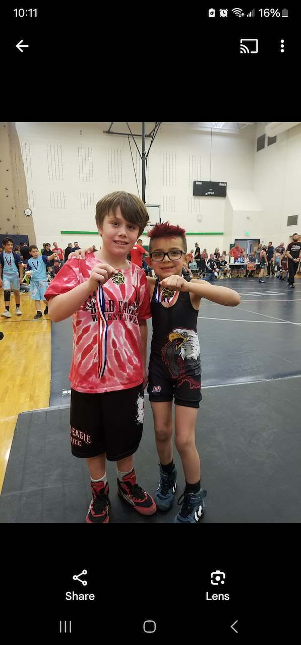 Two young wrestlers holding up their medals in a gym